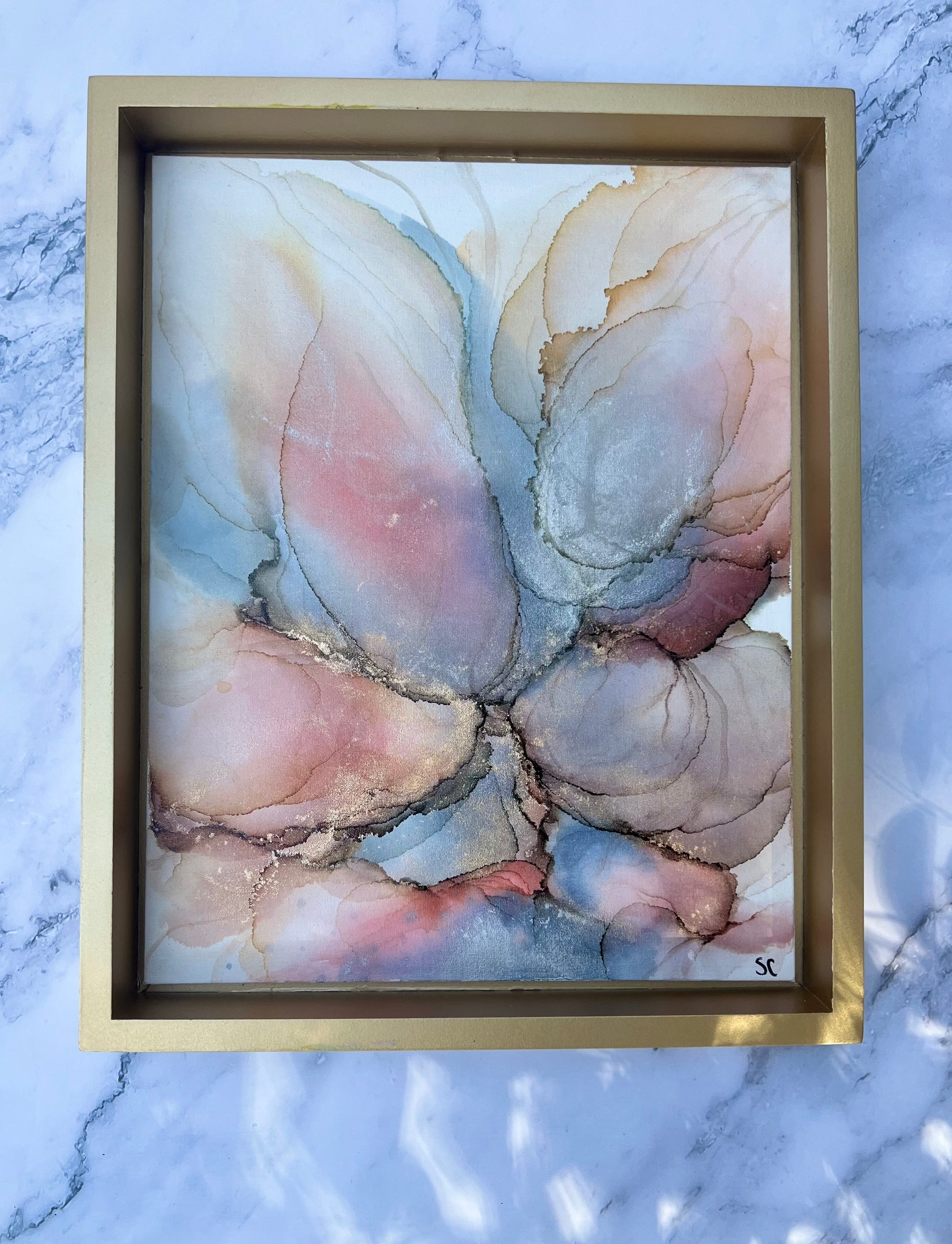 Original alcohol ink painting by Northeast Georgia artist Sarah Campbell, featuring abstract blush, gold, and blue petal-like forms with metallic accents in a gold frame.